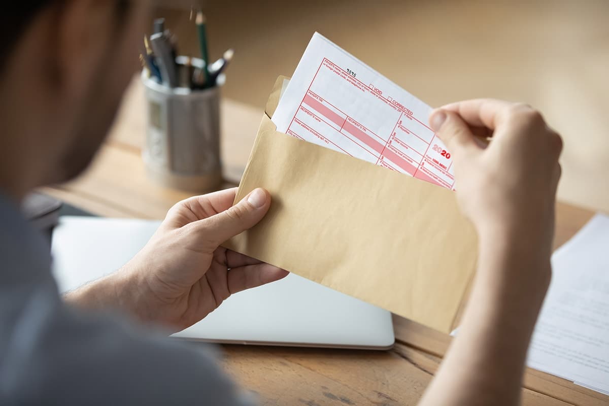 office worker sitting at desk opening envelope with a tax form